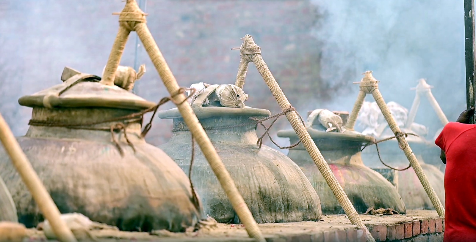 Traditional Kannauj deg vessel heated over a fire for attar distillation