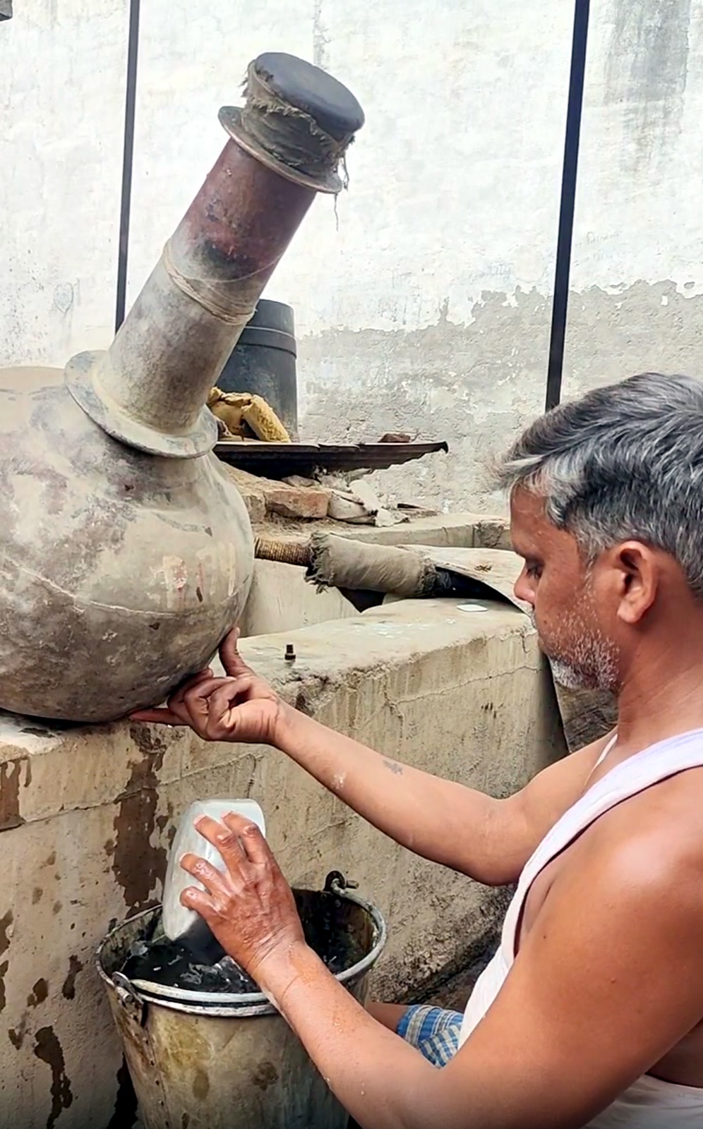 Oil and water separating in a bhapka during traditional Kannauj attar distillation